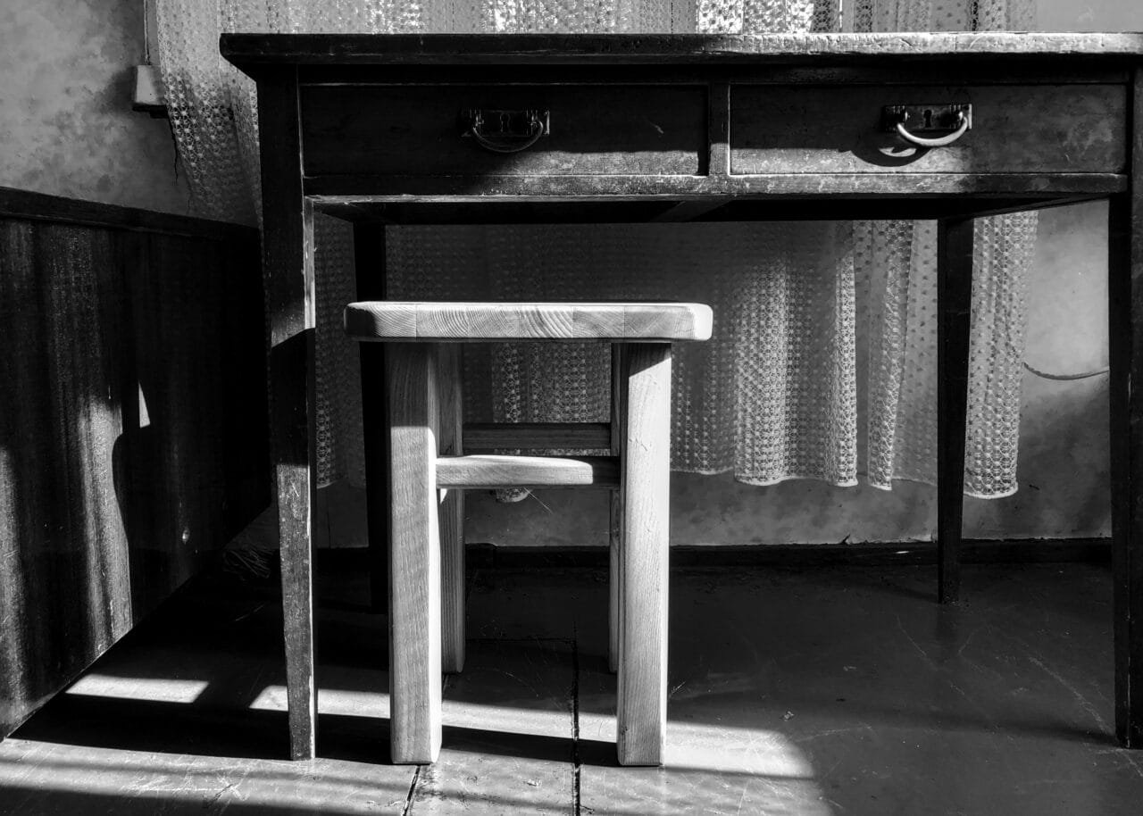 A monochrome image of a table and stool, showcasing simplicity and minimalism