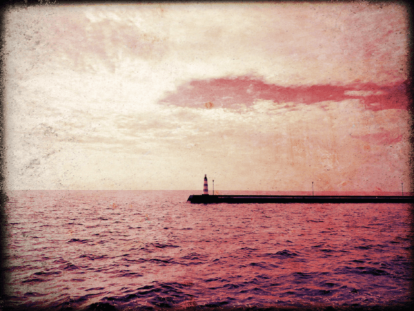 A lighthouse in the distance surrounded by red water